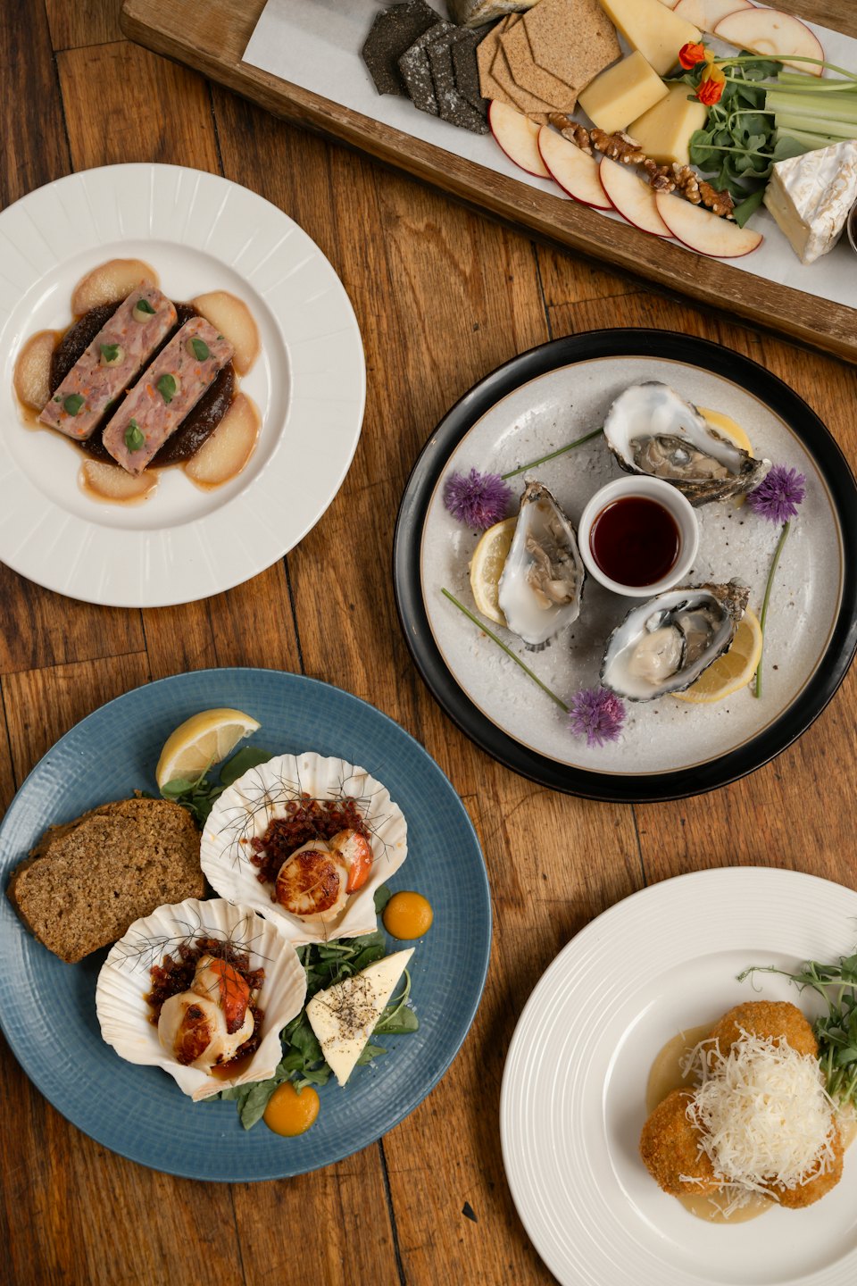 Gourmet dishes and a charcuterie board on a wooden table.