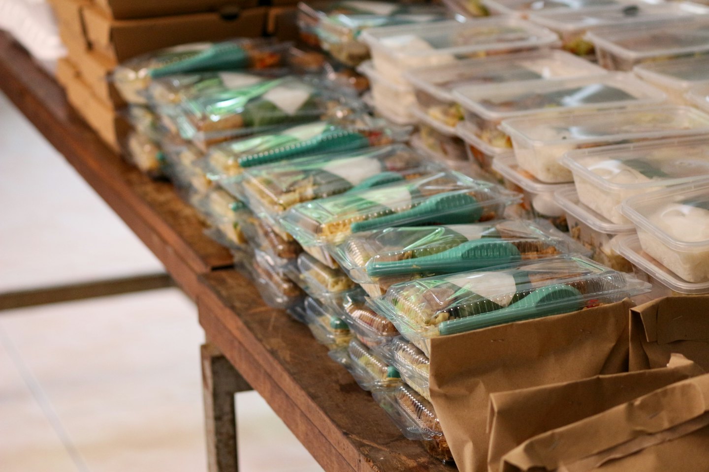 Pre-packaged meals in clear containers stacked on a wooden table.